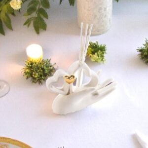 Diffuseur de parfum en forme de main tenant deux cœurs blancs et un cœur doré, posé sur une table décorée – accessoire élégant et romantique.